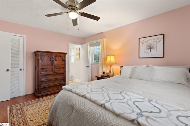 bedroom with a textured ceiling, a ceiling fan, and wood finished floors