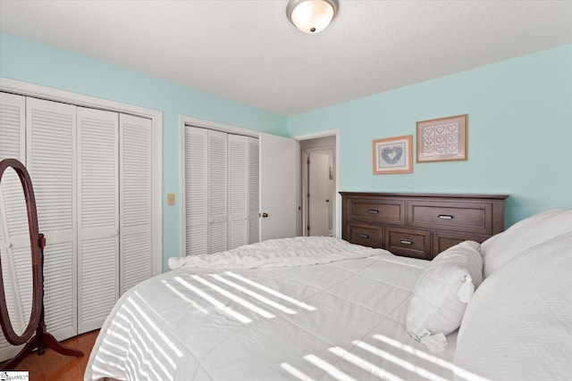 bedroom featuring wood finished floors, multiple closets, and a textured ceiling