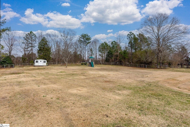 view of yard featuring an outbuilding, a storage unit, a playground, and a fenced backyard