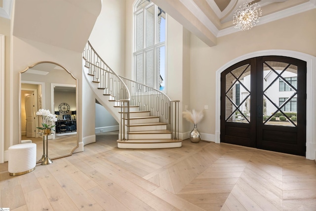 foyer entrance with stairway, arched walkways, a high ceiling, an inviting chandelier, and parquet floors