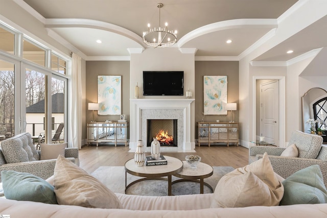 living room with a fireplace with flush hearth, wood finished floors, recessed lighting, crown molding, and a chandelier