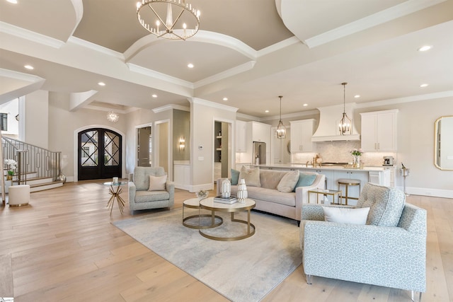 living area with stairway, a notable chandelier, and light wood-style floors