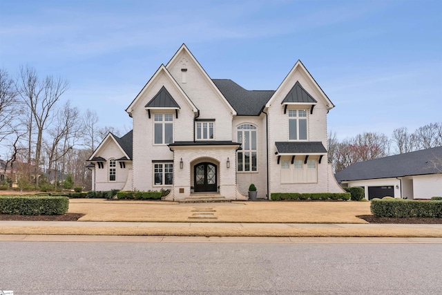 view of front of home featuring brick siding, driveway, metal roof, and a standing seam roof