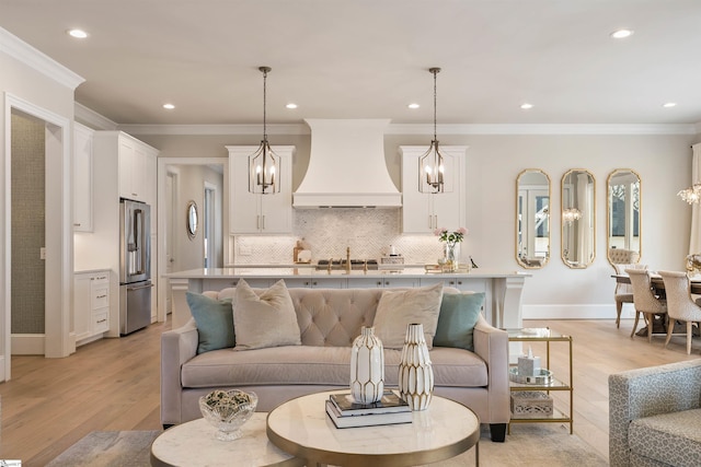 living room featuring a chandelier, recessed lighting, light wood finished floors, and ornamental molding