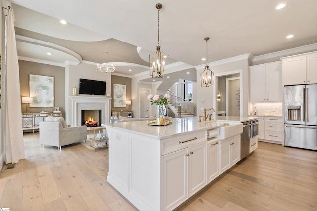 kitchen with white cabinetry, an inviting chandelier, light wood-type flooring, and stainless steel appliances