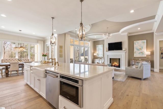 kitchen with light wood-style flooring, appliances with stainless steel finishes, an inviting chandelier, and a sink