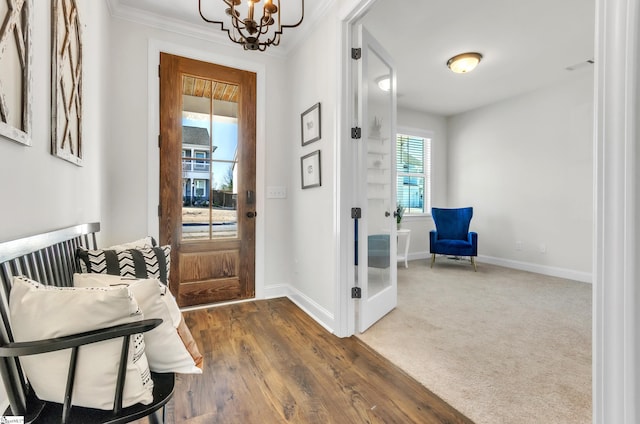 foyer featuring a notable chandelier, baseboards, dark wood-style flooring, and ornamental molding