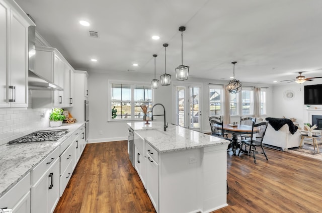 kitchen with stainless steel gas cooktop, open floor plan, decorative backsplash, white cabinets, and dark wood-style flooring