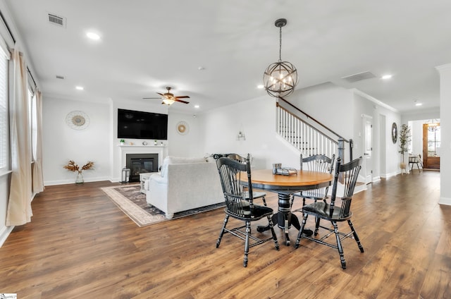 dining room featuring visible vents, ceiling fan with notable chandelier, stairs, and wood finished floors