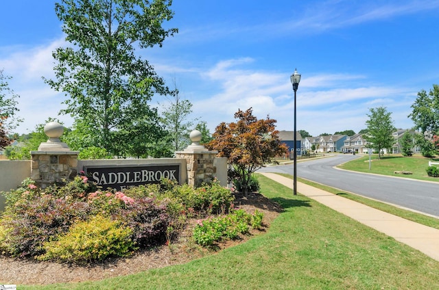 community / neighborhood sign featuring a yard and a residential view