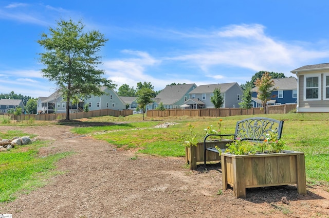 view of yard featuring a vegetable garden, fence, and a residential view