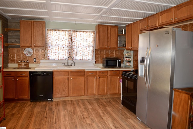 kitchen featuring brown cabinets, black appliances, and light countertops