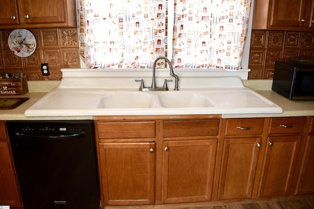 kitchen featuring black appliances, light countertops, brown cabinets, and a sink