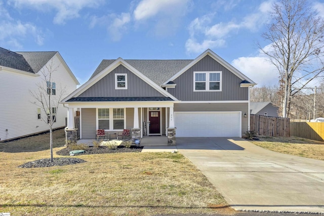 craftsman-style home featuring fence, driveway, a porch, stone siding, and a garage