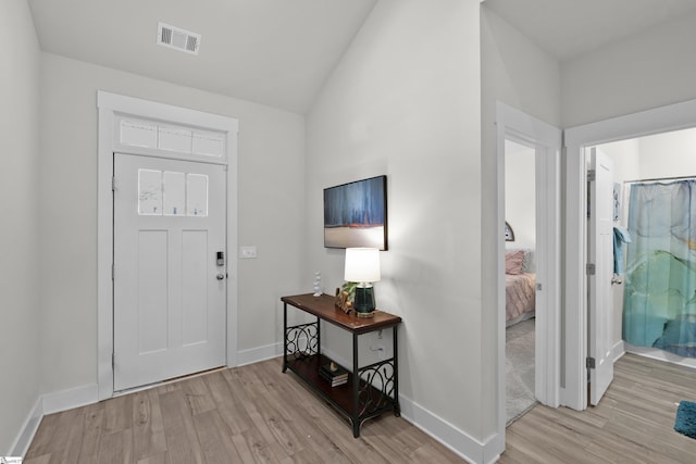 entryway with lofted ceiling, baseboards, visible vents, and light wood-type flooring