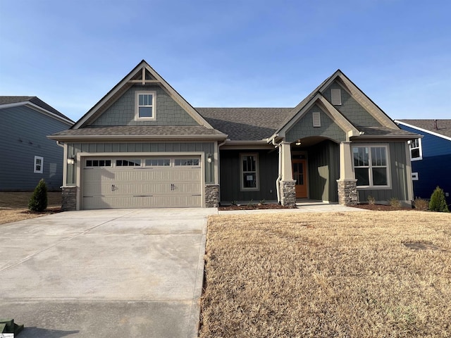 craftsman inspired home featuring concrete driveway, board and batten siding, stone siding, and a shingled roof