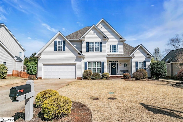 traditional home with a front lawn, concrete driveway, a garage, and fence