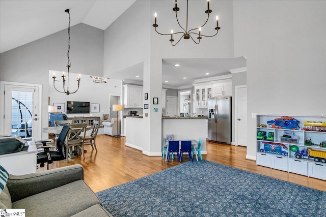 living area with high vaulted ceiling, an inviting chandelier, and wood finished floors