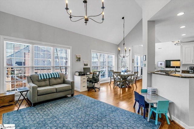 living room featuring high vaulted ceiling, wood finished floors, recessed lighting, baseboards, and a chandelier