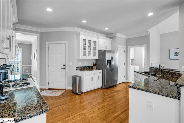 kitchen with white cabinets, stainless steel fridge, light wood finished floors, and a sink