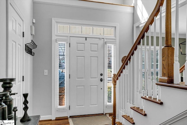 entryway featuring baseboards, wood finished floors, and stairs