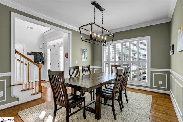 dining space with stairway, wood finished floors, visible vents, ornamental molding, and a notable chandelier