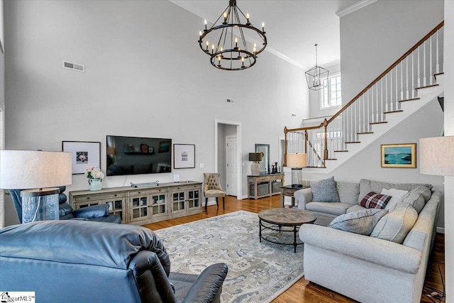 living room featuring visible vents, wood finished floors, stairs, and a chandelier