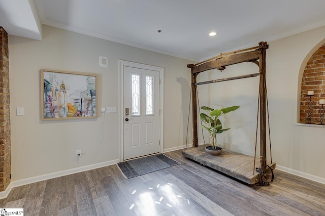 foyer entrance with baseboards, wood finished floors, arched walkways, and ornamental molding