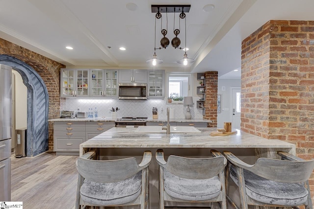 kitchen with tasteful backsplash, light wood-style floors, gray cabinets, and stainless steel appliances