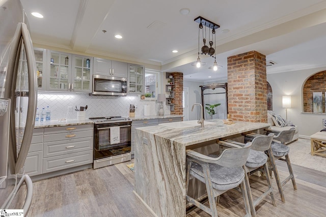 kitchen featuring light wood-type flooring, gray cabinetry, ornamental molding, a sink, and appliances with stainless steel finishes