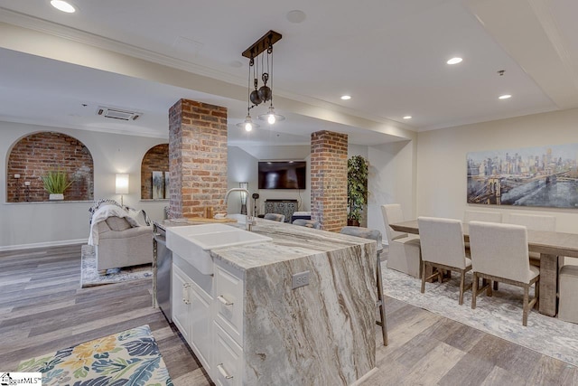 kitchen featuring a sink, light wood-style floors, open floor plan, and ornamental molding