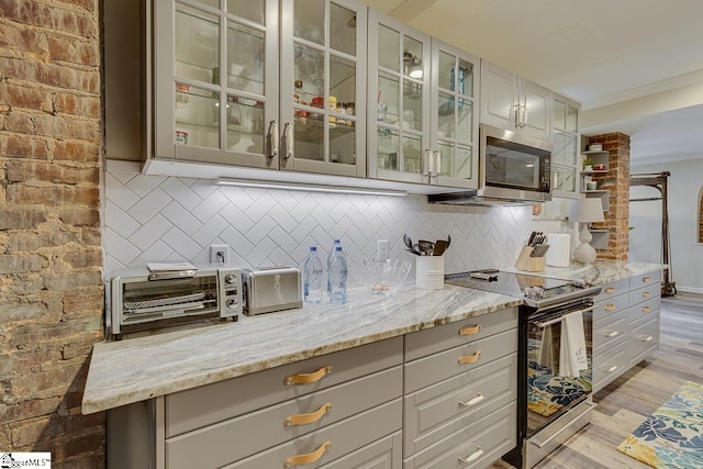 kitchen with stainless steel microwave, light wood-type flooring, ornamental molding, decorative backsplash, and electric stove