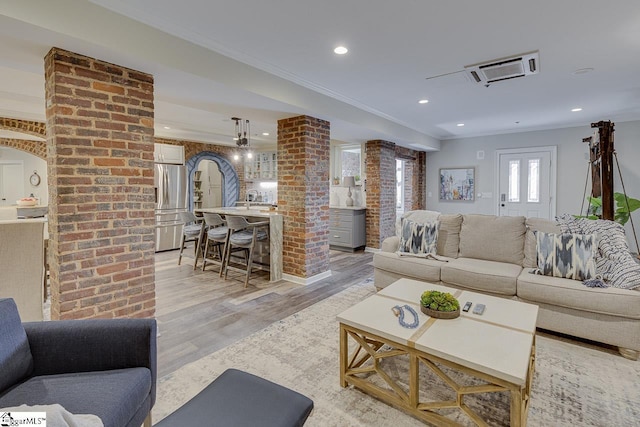 living area featuring recessed lighting, ornamental molding, light wood-type flooring, and decorative columns