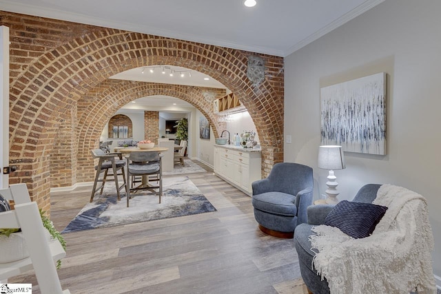 dining space featuring wood finished floors, arched walkways, and brick wall