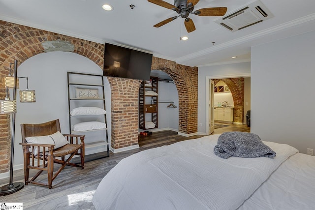 bedroom with visible vents, brick wall, crown molding, wood finished floors, and arched walkways