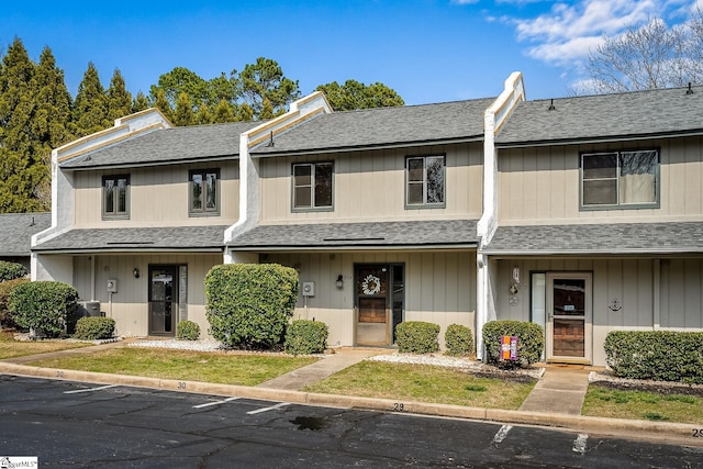 multi unit property with a shingled roof and uncovered parking