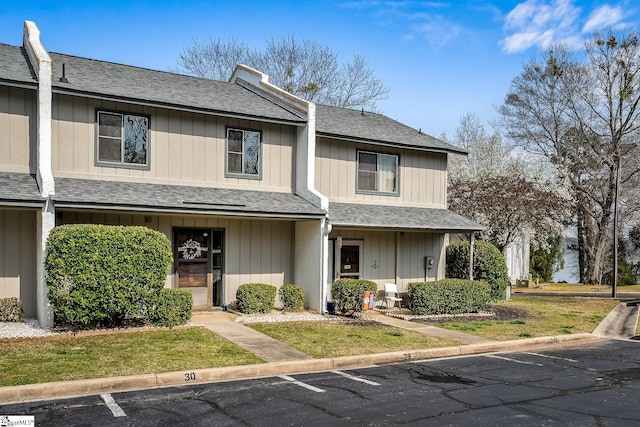 multi unit property featuring roof with shingles and uncovered parking