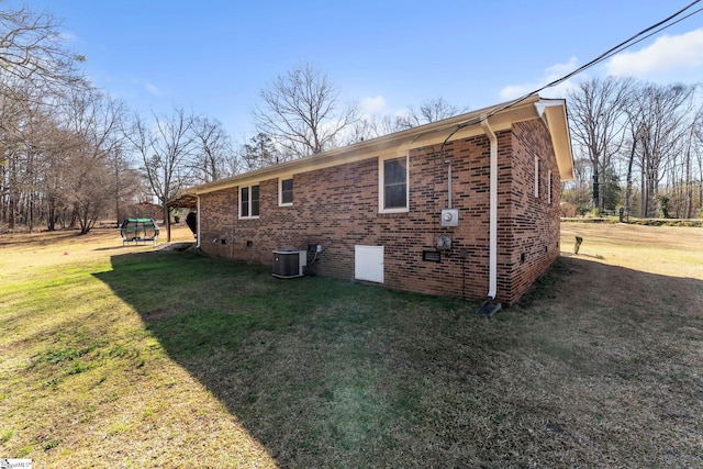 back of house with a yard, central air condition unit, and brick siding