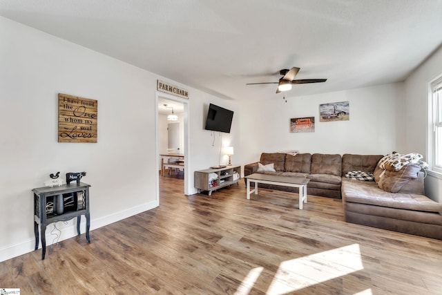 living area with baseboards, a ceiling fan, and wood finished floors