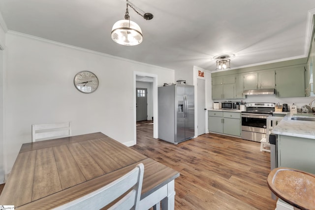 kitchen with under cabinet range hood, appliances with stainless steel finishes, green cabinets, and ornamental molding