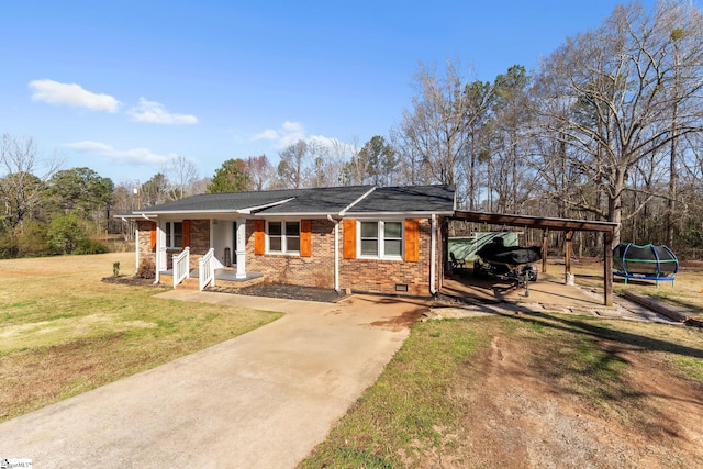 view of front of house featuring brick siding, a front lawn, a trampoline, a carport, and driveway