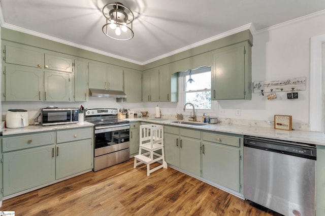 kitchen featuring green cabinets, under cabinet range hood, appliances with stainless steel finishes, and a sink