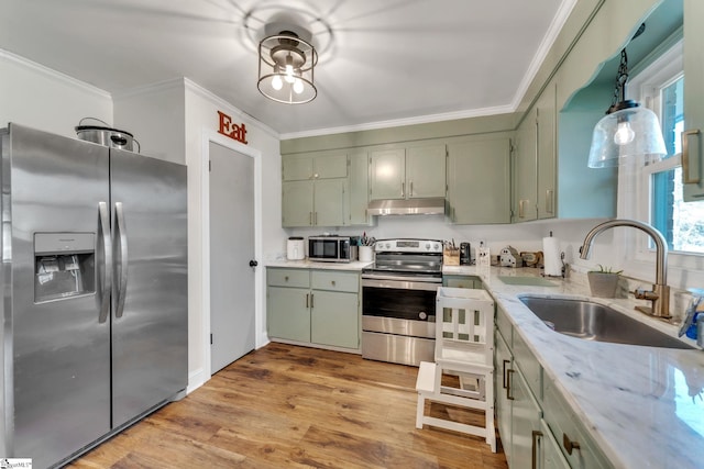 kitchen with ornamental molding, a sink, under cabinet range hood, appliances with stainless steel finishes, and green cabinets