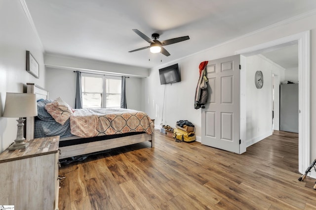 bedroom featuring ceiling fan, wood finished floors, freestanding refrigerator, and ornamental molding