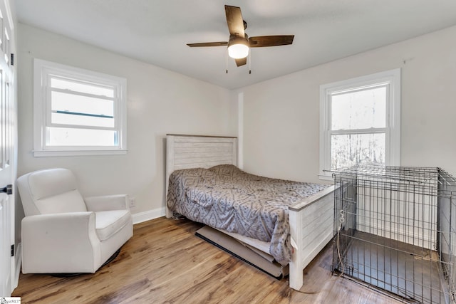 bedroom with baseboards, light wood-type flooring, and ceiling fan