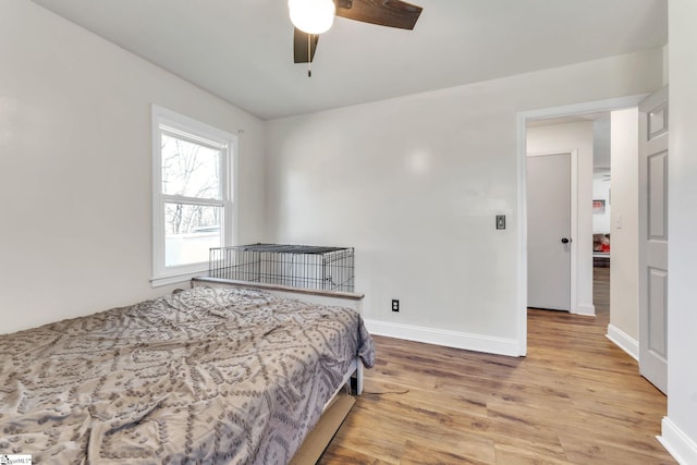 bedroom featuring ceiling fan, baseboards, and wood finished floors