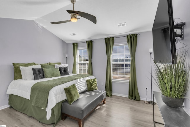 bedroom with vaulted ceiling, wood finished floors, visible vents, and baseboards