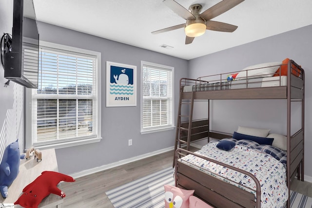 bedroom featuring ceiling fan, wood finished floors, visible vents, and baseboards