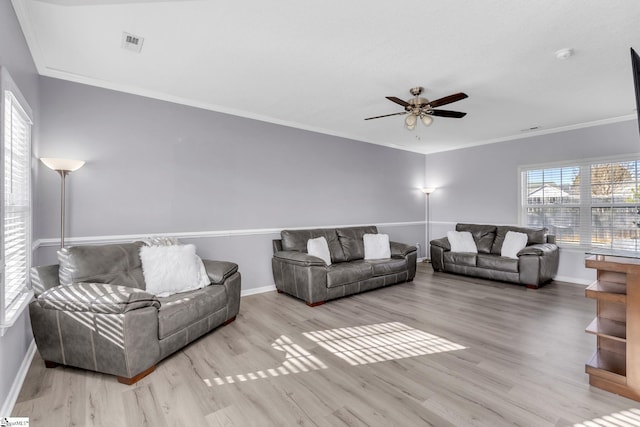 living area featuring visible vents, baseboards, ornamental molding, wood finished floors, and a ceiling fan