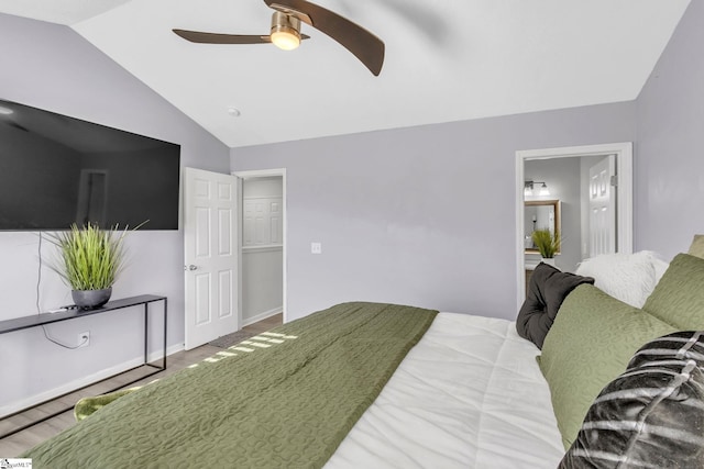 bedroom featuring wood finished floors, connected bathroom, baseboards, lofted ceiling, and ceiling fan